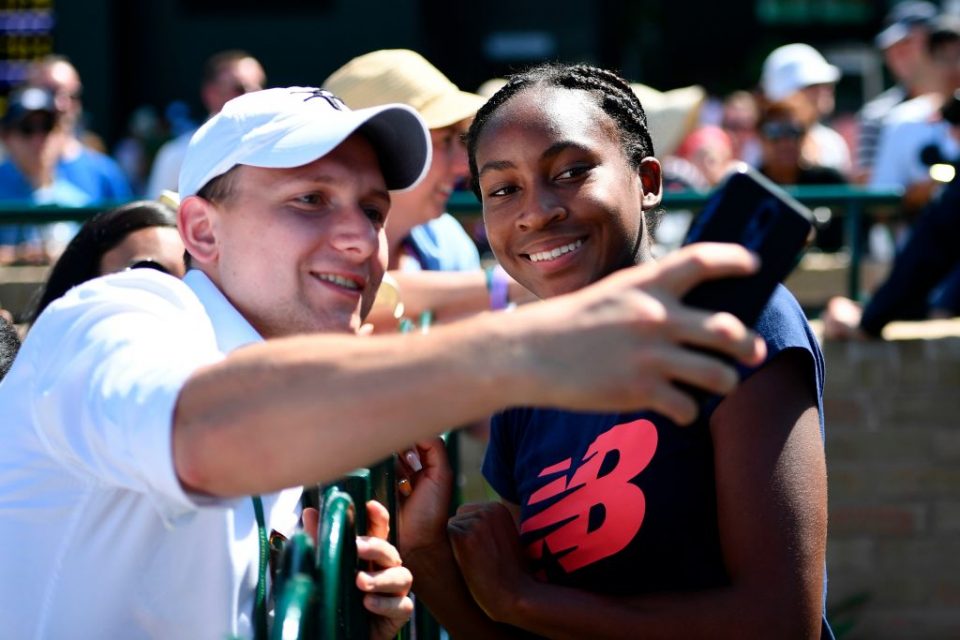 US player Cori Gauff (R) poses for a selfie with fans after a session on the practice courts at The All England Tennis Club in Wimbledon, southwest London, on July 4, 2019, on the fourth day of the 2019 Wimbledon Championships tennis tournament. - Coco Gauff, the 15-year-old schoolgirl who stunned five-time champion Venus Williams in the first round, continued her Wimbledon dream debut on Wednesday when she eased into the last 32 and claimed: "I can beat anyone." Next up for Gauff is a last 32 clash against world number 60 Polona Hercog of Slovenia on July 5. (Photo by Daniel LEAL-OLIVAS / AFP) / RESTRICTED TO EDITORIAL USE (Photo credit should read DANIEL LEAL-OLIVAS/AFP/Getty Images)