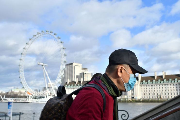 UK coronavirus: A man wears a face mask as he walks along the Thames embankment in central London