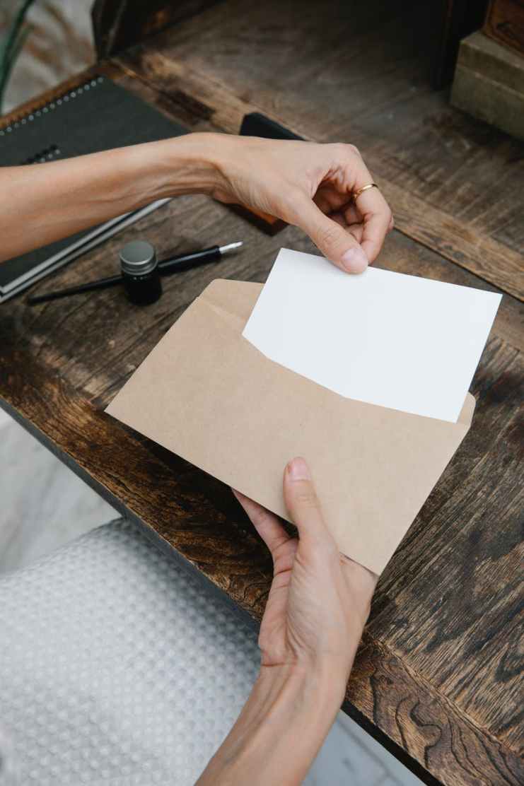 crop unrecognizable woman placing blank paper in envelope