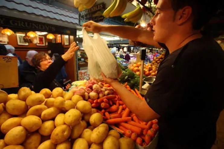 A a stall holder sells vegetables to a customer at Bolton Market. Inflation is set to continue rising