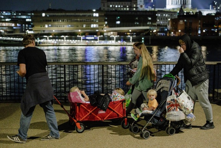 A family stands in line on the Southbank as tens of thousands join queues to see Queen Elizabeth II lying in state at Westminster Hall. (Photo by Rob Pinney/Getty Images)