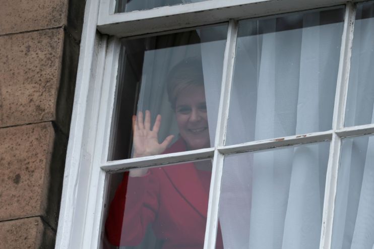 Nicola Sturgeon waves from a window, after holding a press conference (Photo by Jeff J Mitchell/Getty Images)