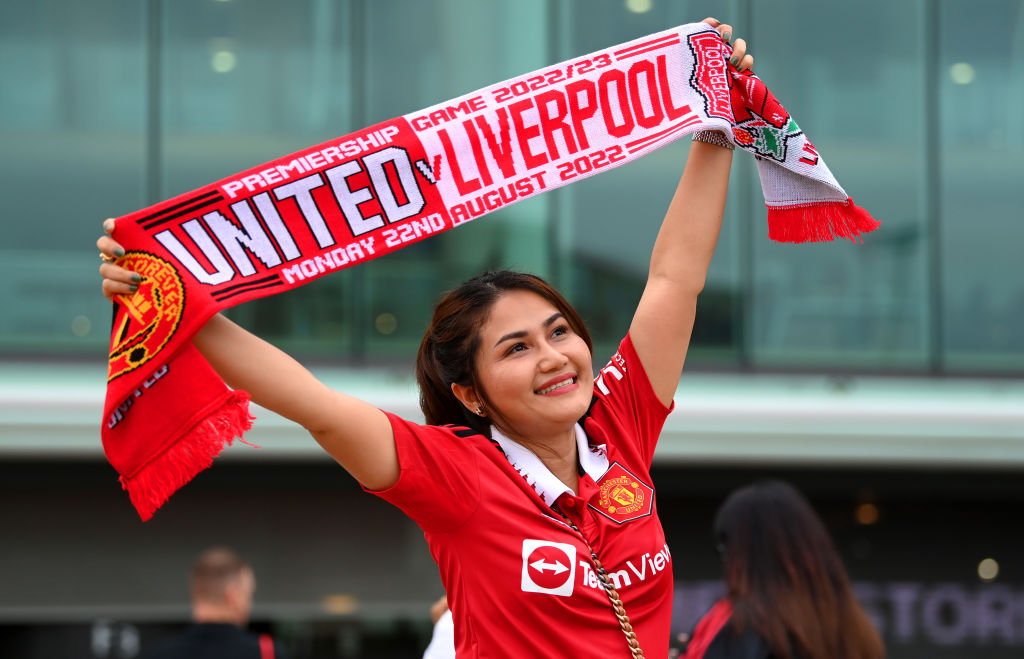 MANCHESTER, ENGLAND - AUGUST 22: A Manchester United fan poses for a photo with a half and half scarf outside the stadium prior to the Premier League match between Manchester United and Liverpool FC at Old Trafford on August 22, 2022 in Manchester, England. (Photo by Michael Regan/Getty Images)