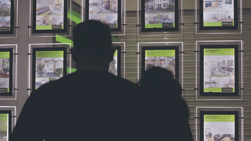 People looking at homes for sale in an estate agents window