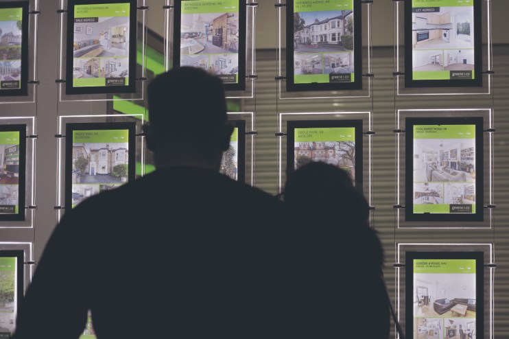 People looking at homes for sale in an estate agents window