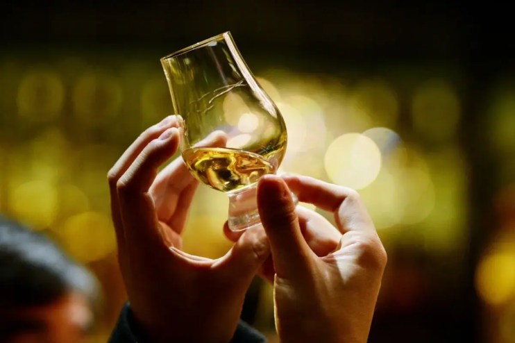 A pair of hands holding a glass of whisky