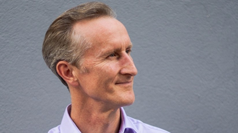 Image of a man in a purple collared shirt looking to his left