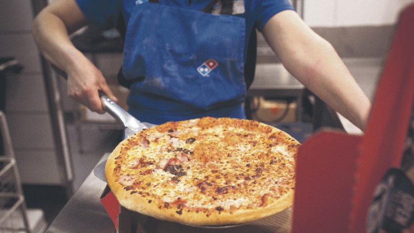 An employee places a cooked pizza into a delivery box inside a Domino's Pizza Group in London. Photographer: Jason Alden/Bloomberg via Getty Images