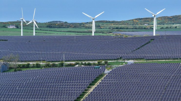ANGLESEY, WALES - MAY 10: In this aerial view wind turbines can be seen next to the North Anglesey Solar Project at Porth Wen, May 10, 2024 in Anglesey, Wales. Porth Wen is a 50MW Solar and Battery farm completed by Countryside Renewables in 2023. It will contribute to Wales’ overall goal of the country generating 70% of its electricity consumption from renewables by 2030 and reducing its carbon emissions by at least 95% by 2050. Plans have been submitted to build more solar farms on the island, with a capacity of 350MW which will produce enough energy to power 133,106 homes and cover 12.34 sq km of farmland. (Photo by Christopher Furlong/Getty Images)