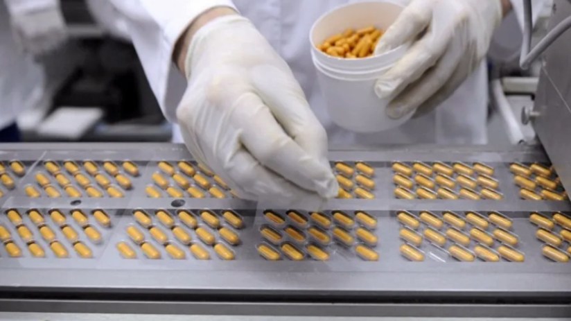 Worker at a medicine factory placing pills into viles