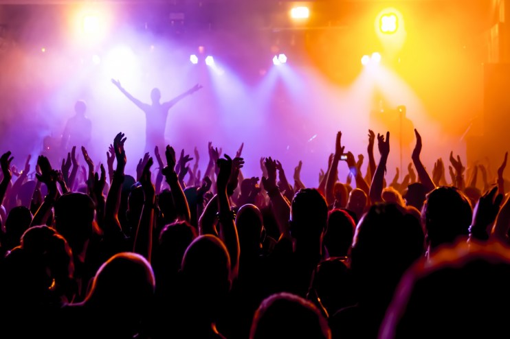 A group of concert goers at a gig, which Midwich provides lighting to