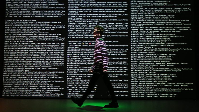 LONDON, ENGLAND - DECEMBER 02: A staff member stands in a projection of live data feeds from (L-R) Twitter, Instagram and Transport for London by data visualisation studio Tekja at the Big Bang Data exhibition at Somerset House on December 2, 2015 in London, England. The show highlights the data explosion that's radically transforming our lives. It opens on December 3, 2015 and runs until February 28, 2016 at Somerset House. (Photo by Peter Macdiarmid/Getty Images for Somerset House)