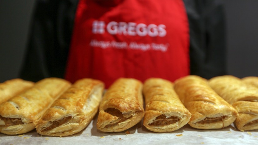 An employee holds a tray of freshly baked sausage rolls in a Greggs (Photographer: Chris Ratcliffe/Bloomberg via Getty Images)