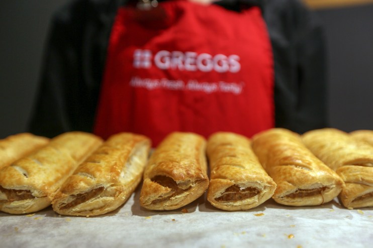 An employee holds a tray of freshly baked sausage rolls in a Greggs (Photographer: Chris Ratcliffe/Bloomberg via Getty Images)
