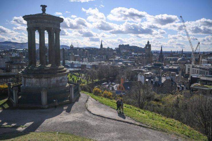 EDINBURGH, SCOTLAND - APRIL 09: People jog at Calton Hill Cemetery overlooking the Old Town with Dugald Stewart Monument on Calton Hill as the country responds to the announcement that Prince Philip, Duke Of Edinburgh has died at age 99 on April 9, 2021 in Edinburgh, United Kingdom. The Queen has announced the death of her beloved husband, His Royal Highness Prince Philip, Duke of Edinburgh. HRH passed away peacefully this morning at Windsor Castle. (Photo by Peter Summers/Getty Images)