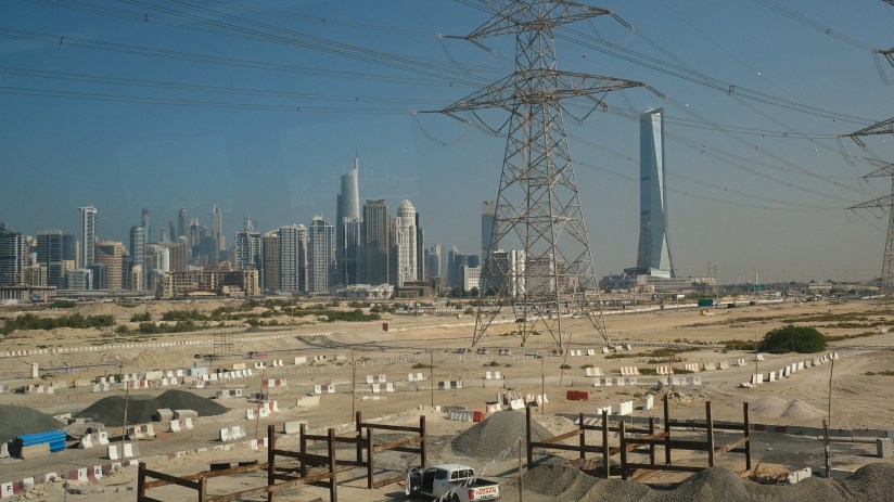 DUBAI, UNITED ARAB EMIRATES - DECEMBER 07: In this view through a metro train window high-rise buildings stand behind electricity power lines and a transmission tower on December 07, 2023 in Dubai, United Arab Emirates. Dubai is one of the seven emirates in the UAE and has become a popular tourist destination. (Photo by Sean Gallup/Getty Images)