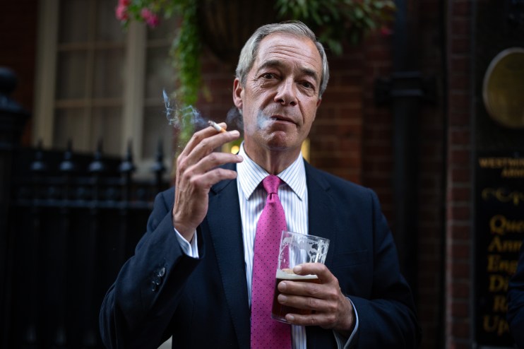 LONDON, ENGLAND - AUGUST 29: Reform UK leader Nigel Farage smokes a cigarette and drinks a pint of ale outside a pub on August 29, 2024 in London, England. The UK government is looking at tougher rules on outdoor smoking to reduce the number of preventable deaths linked to tobacco use. Leader of the Reform UK party, Nigel Farage, said he would never go to a pub again if outside smoking is banned. He accuses the government of ignoring drug abuse, instead implementing policies that will "kill off the traditional pub forever." (Photo by Carl Court/Getty Images)