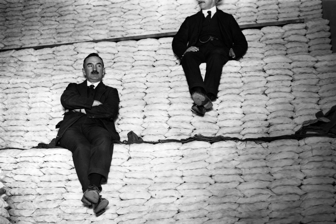 1st June 1923: Two men sitting on a huge pile of coins which after being weighed and packed have been stacked into neat rows at the Royal Mint. (Photo by Hulton Archive/Getty Images)