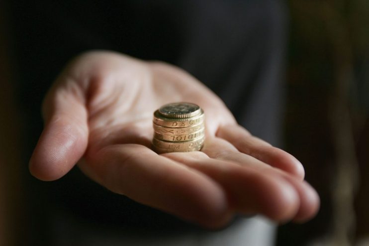 GLASGOW, UNITED KINGDOM - MARCH 11: A hand holding coins on March 11, 2005 in Glasgow, Scotland. As of October 2005 the UK minimum wage will be raised to GBP5.05 from GBP4.85, while 18 to 21 year olds will be paid GBP4.25. An esitmated 1 million people will benefit from the increase. (Photo illustration by Christopher Furlong/Getty Images)